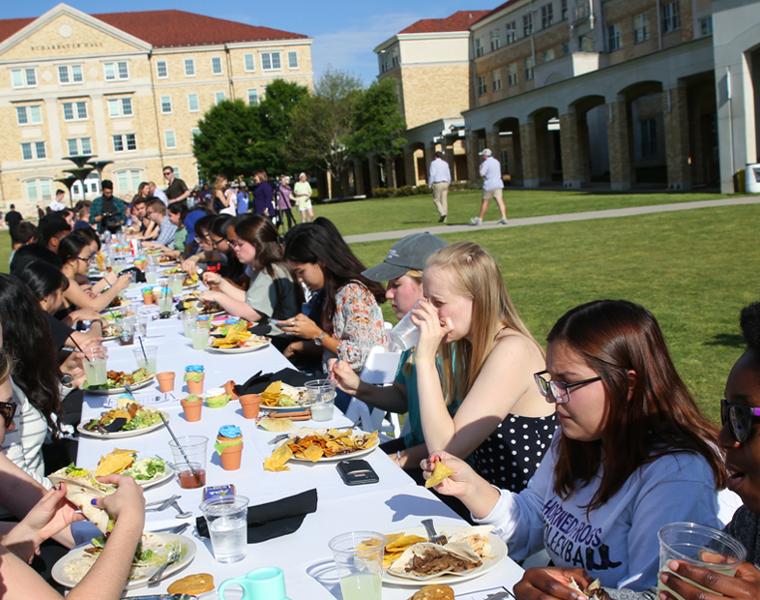 Students eating at a large table in the campus commons at TCU's Common Table event 