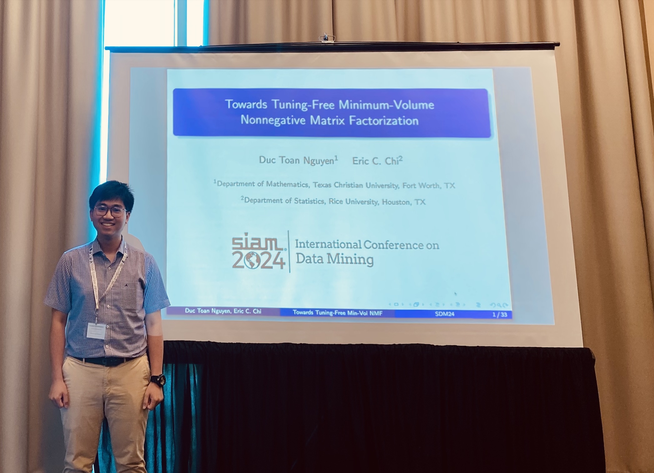 Duc Toan Nguyen standing beside a presentation slide for his research at SIAM SDM24.