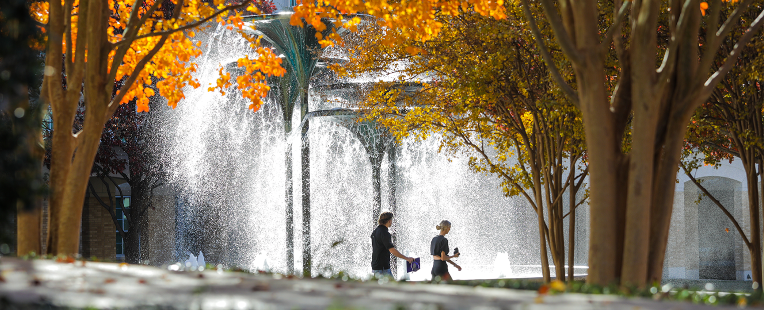 tcu students walking past frog fountain in the fall season