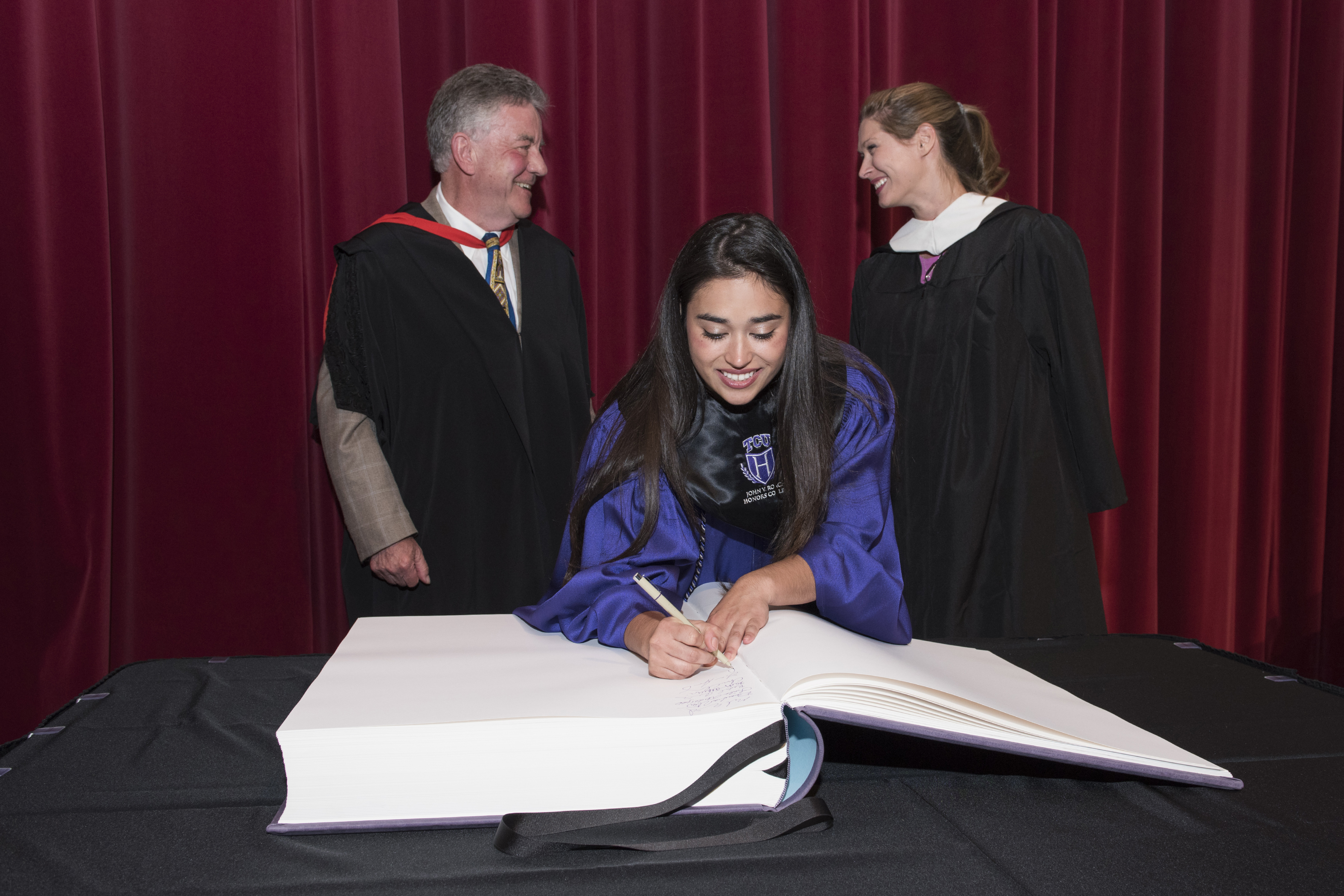 A student adds her name to the John V. Roach Honors College's Roll of Graduates. Photo by Rhonda Misslin, May 2016
