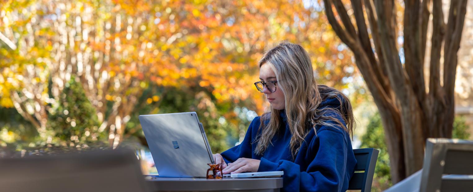 Female student on computer outside