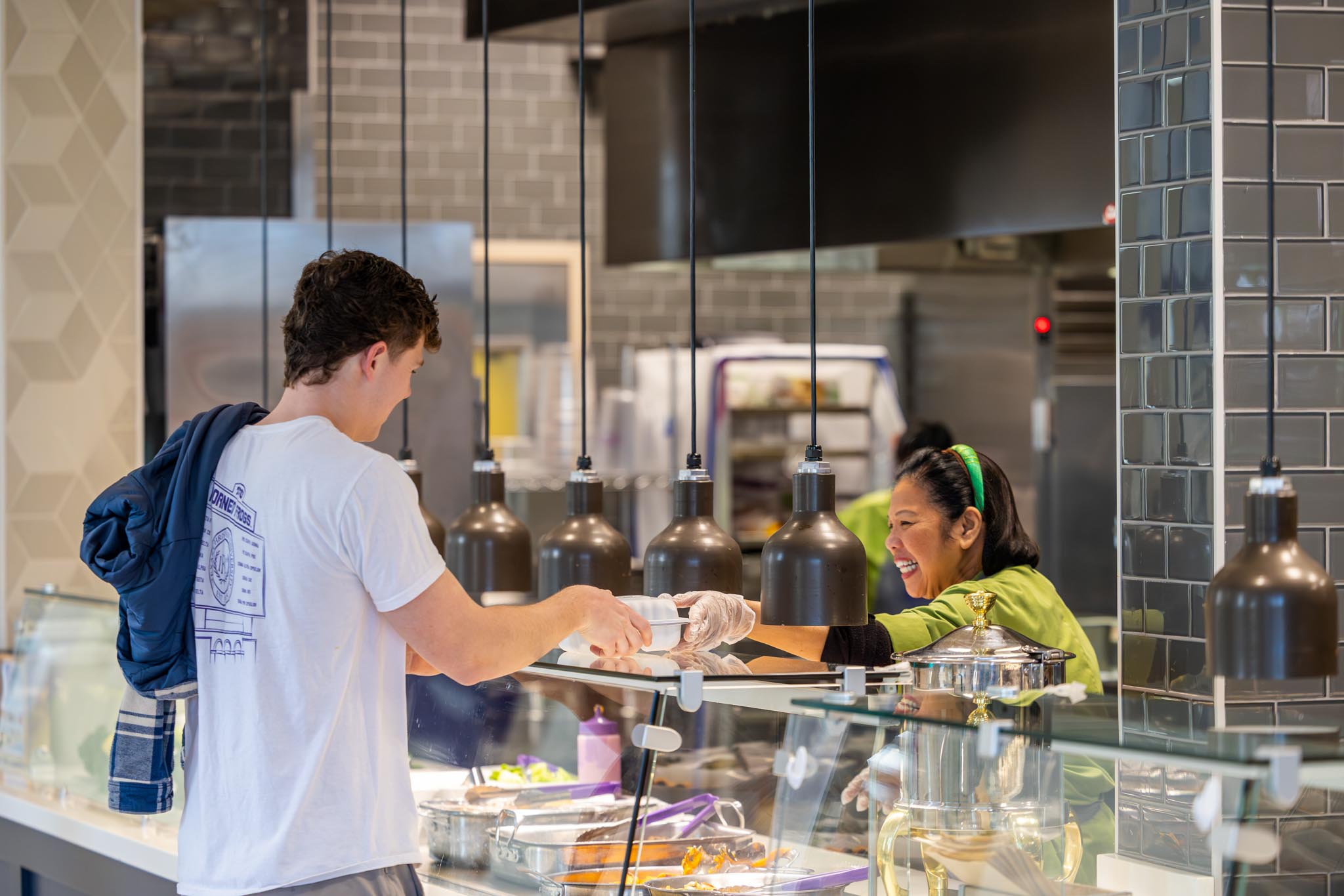 A dining services staff member hands a student his order at a food kiosk in the King Family Commons building, January 24, 2025. Photo by James Anger.