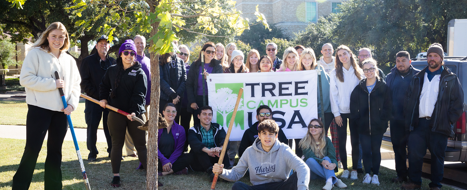 tcu students posing for a photo by tree that was just planted