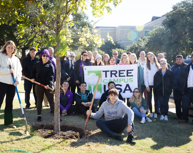 tcu students posing for a photo by tree that was just planted