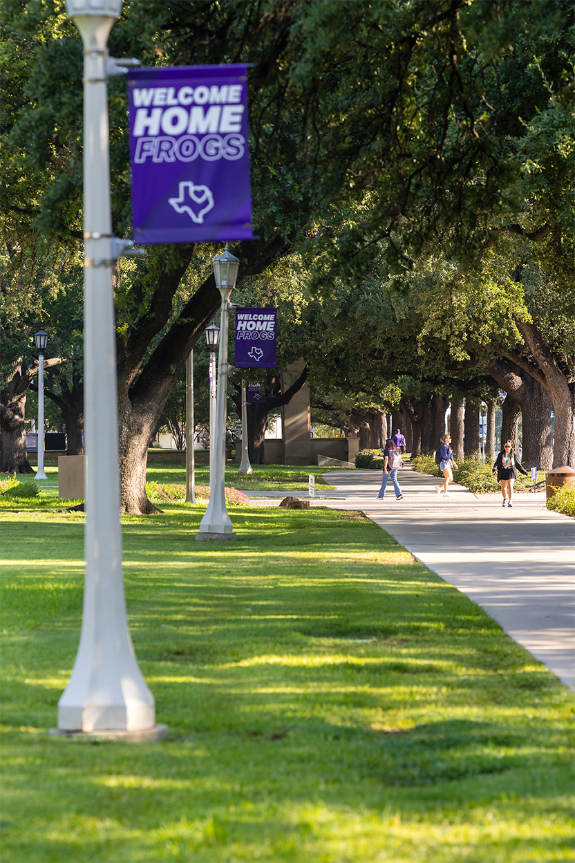 image of tcu light poles with purple banners that say welcome home frogs and students walking in the background