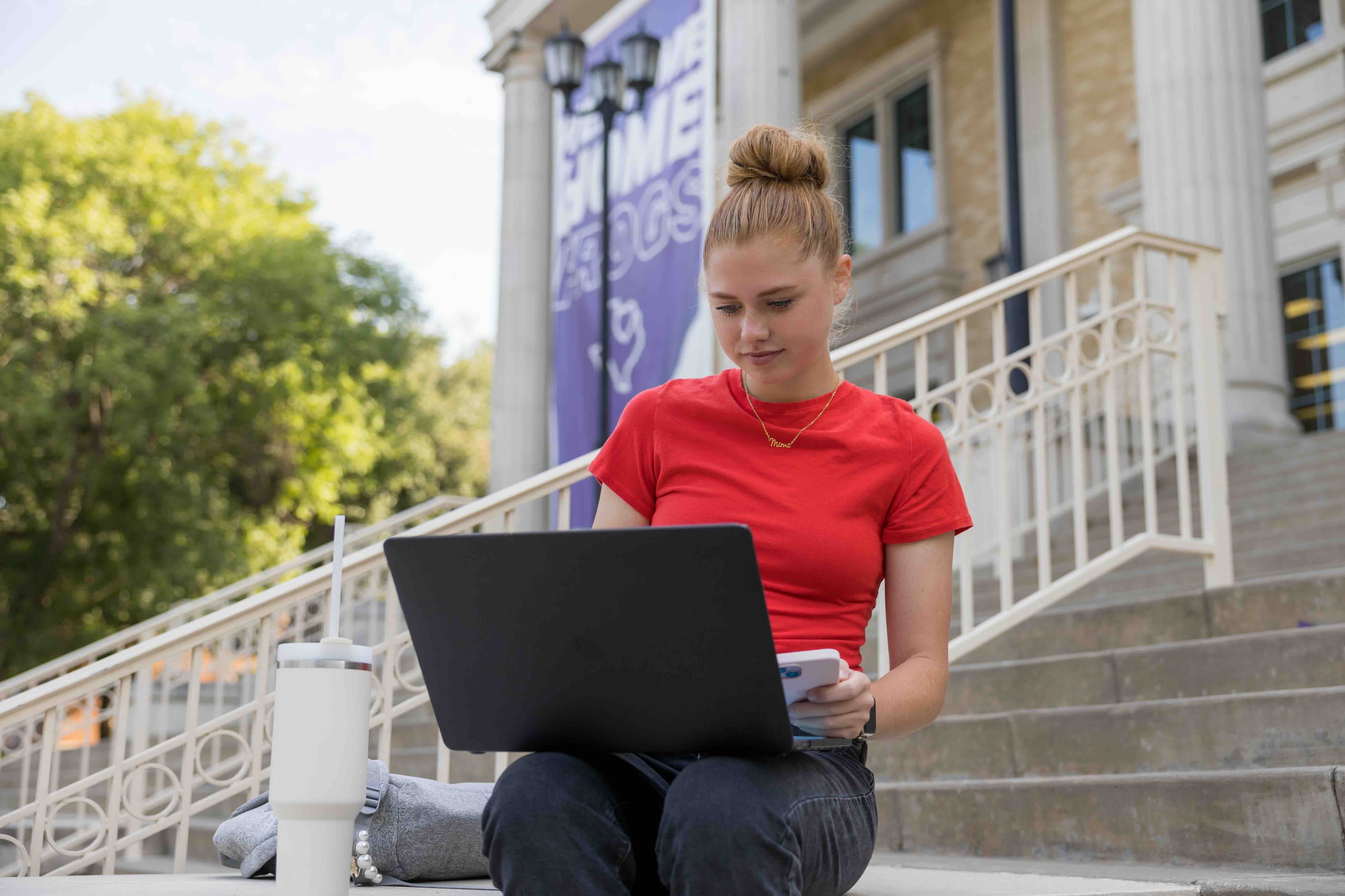 Female student on computer in front of library