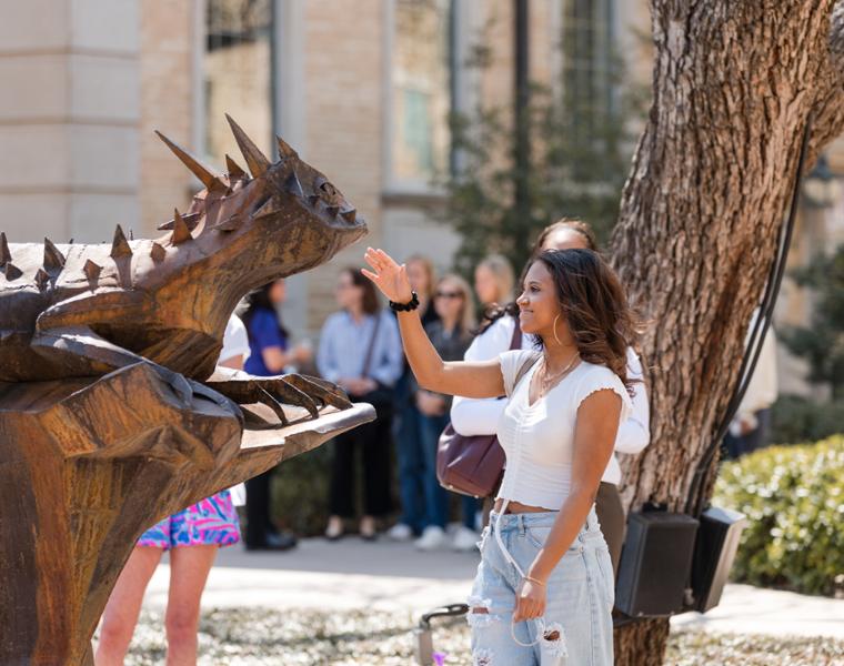 Student rubbing the nose of the Horned Frog statue