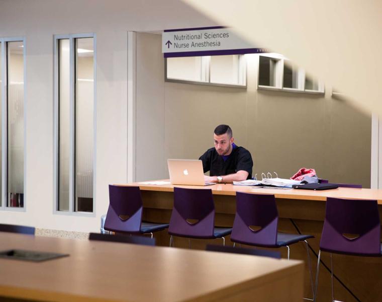 Male student studying at table in the Bass building