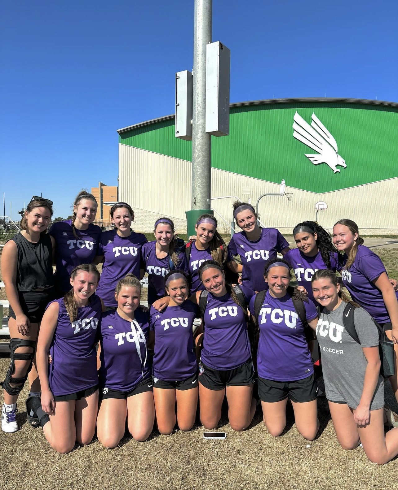 Colleen posing with the tcu club women's soccer team in front of UNT 