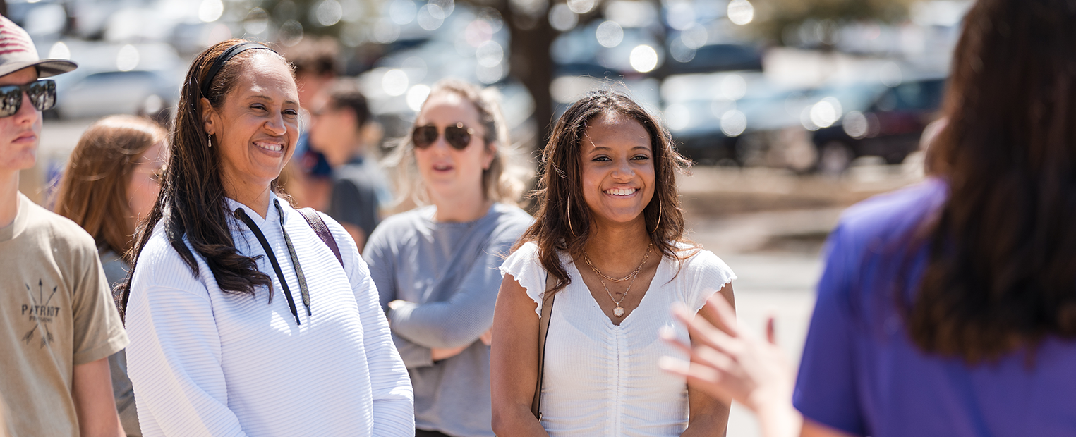 A mother and daughter smiling while listening to a TCU tour guide