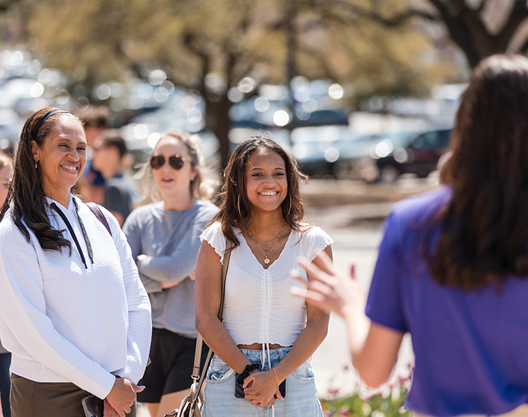 A mother and daughter smiling while listening to a TCU tour guide