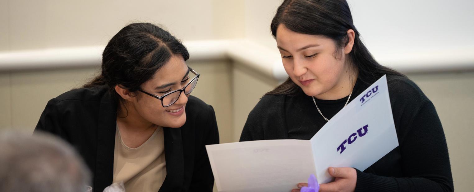 Two female prospective students looking at brochures.