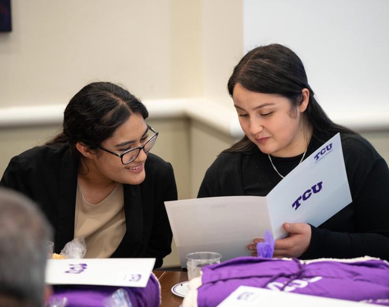 Two female prospective students looking at brochures.