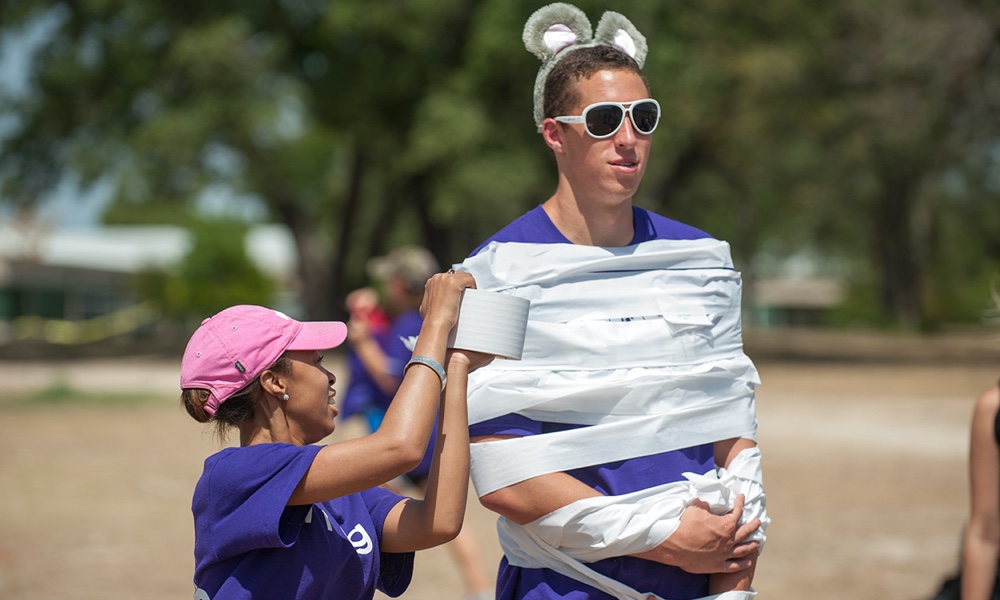 Student wearing bunny ears, being wrapped in toilet paper