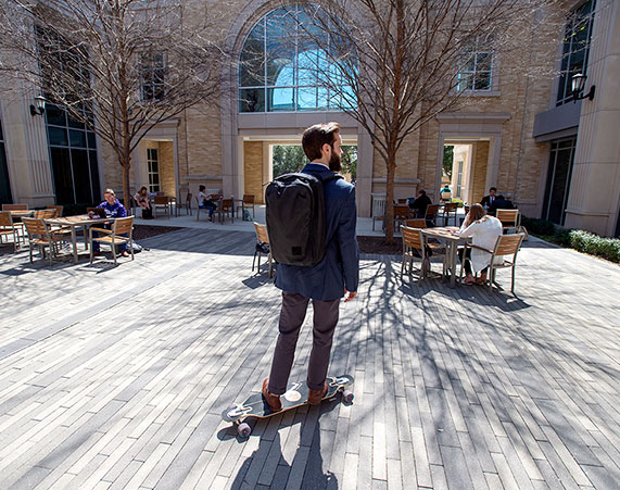 A TCU business school student skateboards through campus