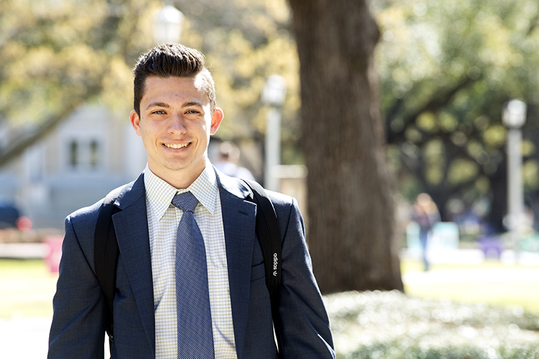 Male TCU student in suit walks through campus