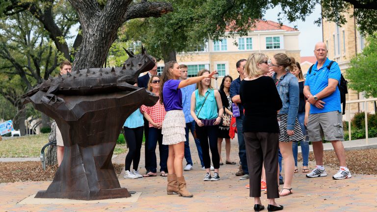 A campus tour group gathered new a horned frog statue