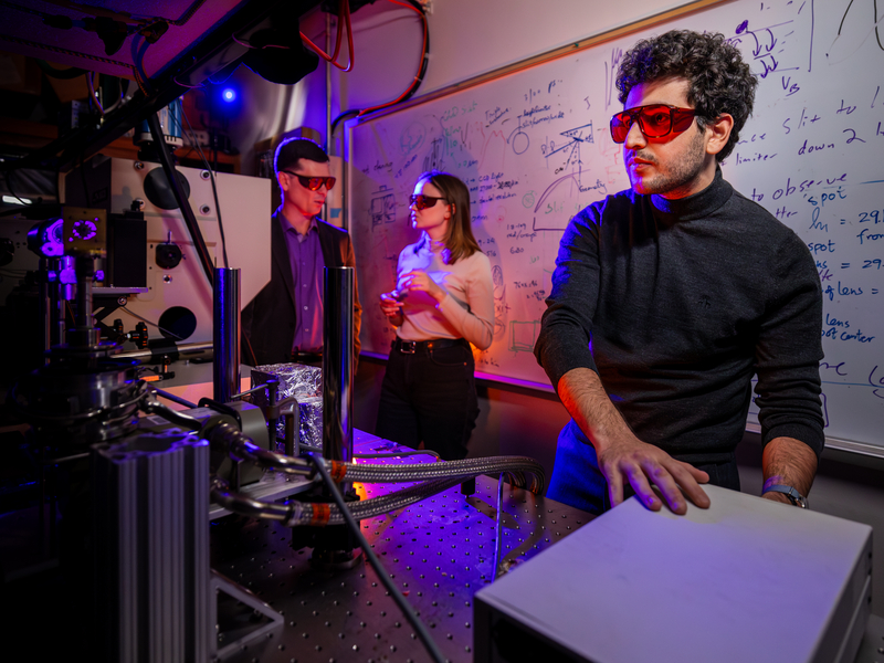Professor works with students in a science lab. 