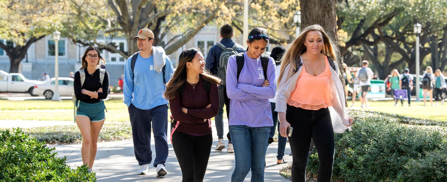 students walking on campus wearing backpacks